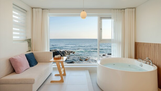 A modern bathroom with a large bathtub and a view of the ocean. - Donghae Badadam Ocean View Spa Pension (Donghae)