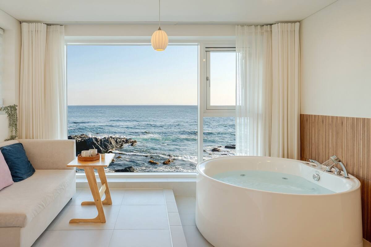A modern bathroom with a large bathtub and a view of the ocean.