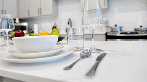 Una cocina moderna con armarios blancos, encimera de mármol, un cuenco de fruta y una copa de vino.
