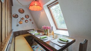 Un comedor con una mesa larga dispuesta para dos comensales, una lámpara colgante y un ventanal con vistas.
