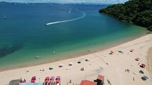 Une plage avec une eau cristalline, des bateaux et des parasols.