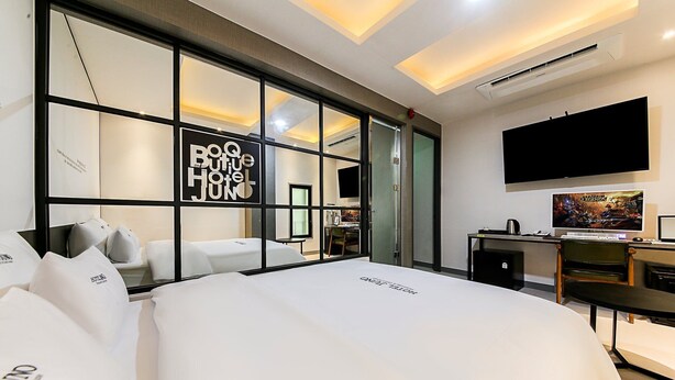 A modern hotel room with a large bed, a desk with a computer, a flat-screen TV, and a large window with a view. - HOTEL JUNO (Yongin)