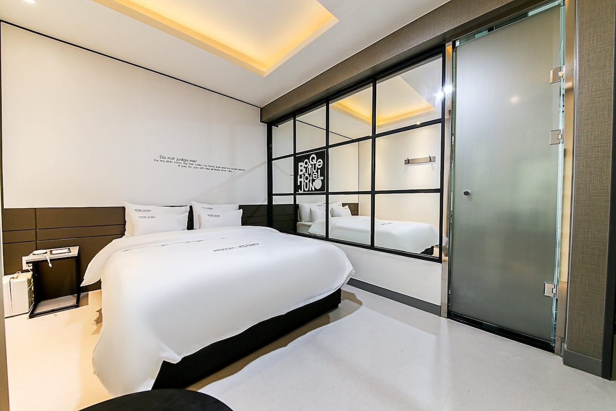 Una habitación de hotel moderna con una cama grande, un mamparo de vidrio y una frase motivadora en la pared.