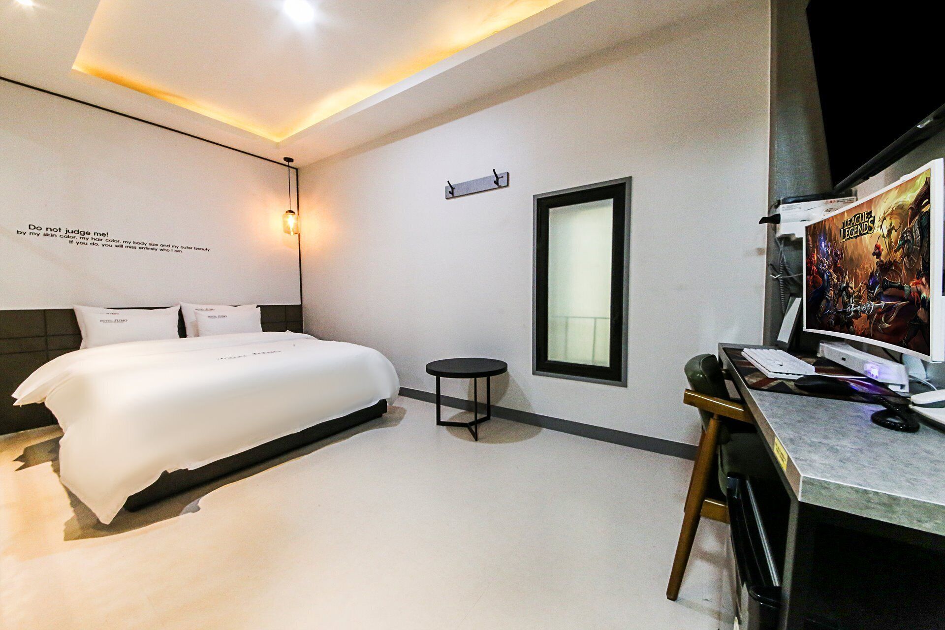 Habitación de hotel moderna con una cama grande, un escritorio con computadora y un televisor de pared.
