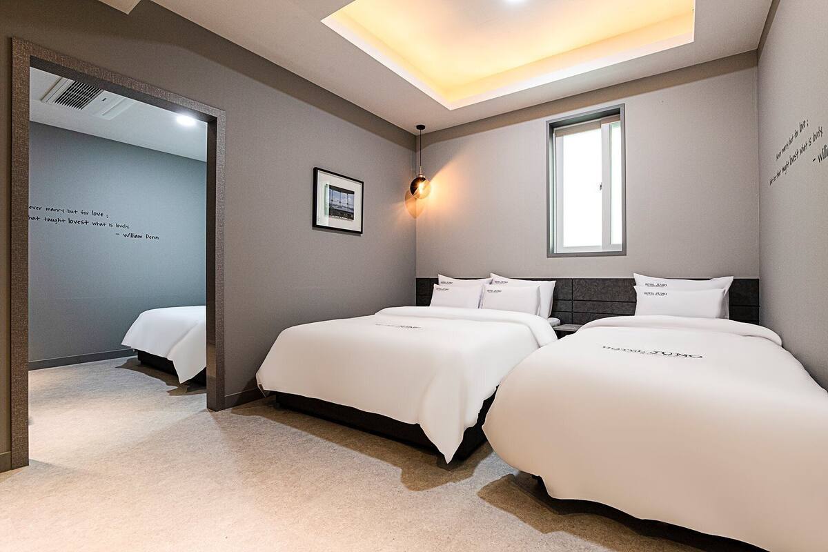 Una habitación de hotel con dos camas, un tragaluz, una cita enmarcada en la pared y una ventana.