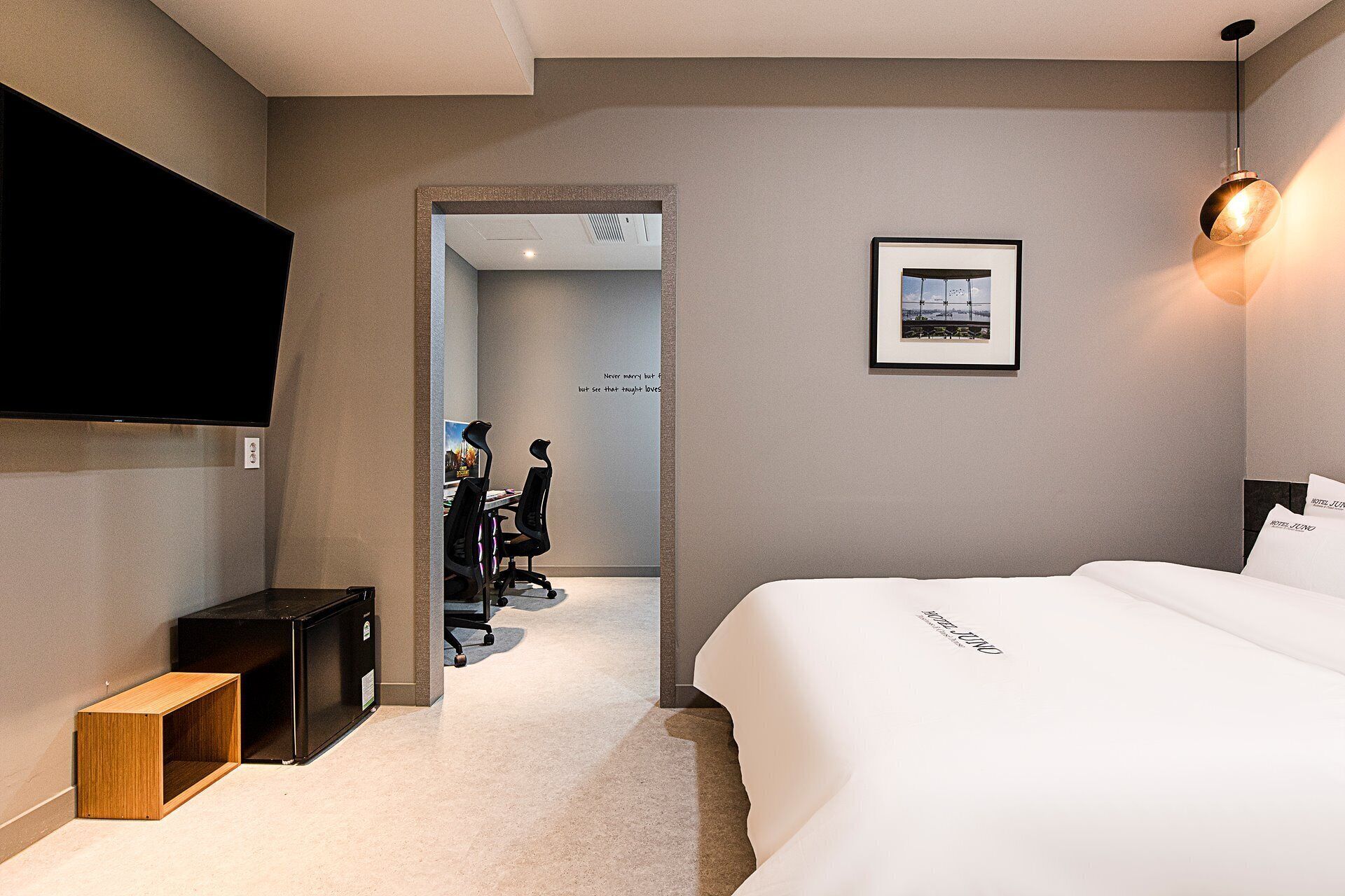 Habitación de hotel con una cama, un escritorio, una silla, un televisor y un cuadro en la pared.