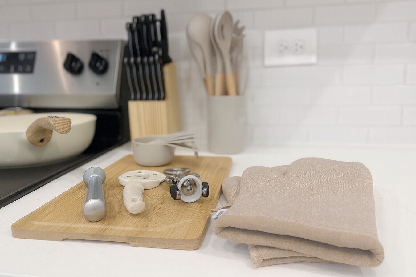 A kitchen counter with a cutting board, kitchen tools, and a folded towel.