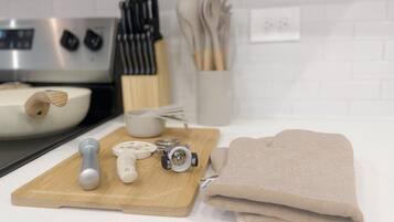 A kitchen counter with a cutting board, kitchen tools, and a folded towel.