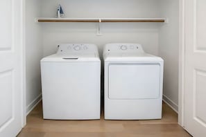 Ein Waschraum mit zwei weißen Waschmaschinen mit Frontlader und einem Regal darüber.