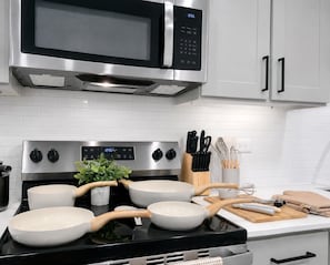 Une cuisine équipée d’un four à micro-ondes, d’une cuisinière, de casseroles et d’ustensiles de cuisine.