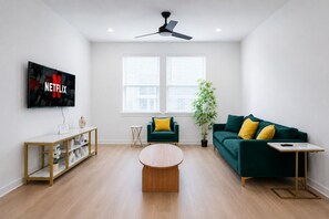 A modern living room with a flat-screen TV, two sofas, a coffee table, and a ceiling fan. - Modern Stay WorkerFriendly Home w/Lndry GYM & Pool (Sherman)
