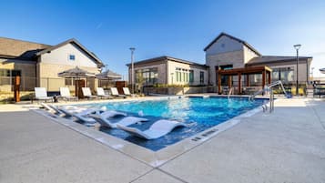 A swimming pool with lounge chairs and a covered seating area.