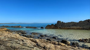 A coastal landscape with rocky terrain and clear blue waters. - Pebbly Beach Escape | Sea View (Forster)
