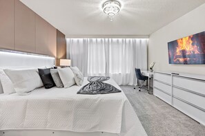 Ein modernes Hotelzimmer mit einem großen Bett, einem Schreibtisch und einem Flachbildfernseher, der ein Feuer zeigt.