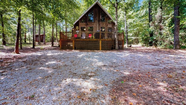A cabin with a deck, surrounded by trees. - 1 Mi to Pickwick Lake! Tranquil Wooded Cabin (Iuka)