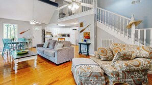 A spacious living area with a high ceiling, a staircase, and a kitchen in the background. - 1 Mi to Pickwick Lake! Tranquil Wooded Cabin (Iuka)