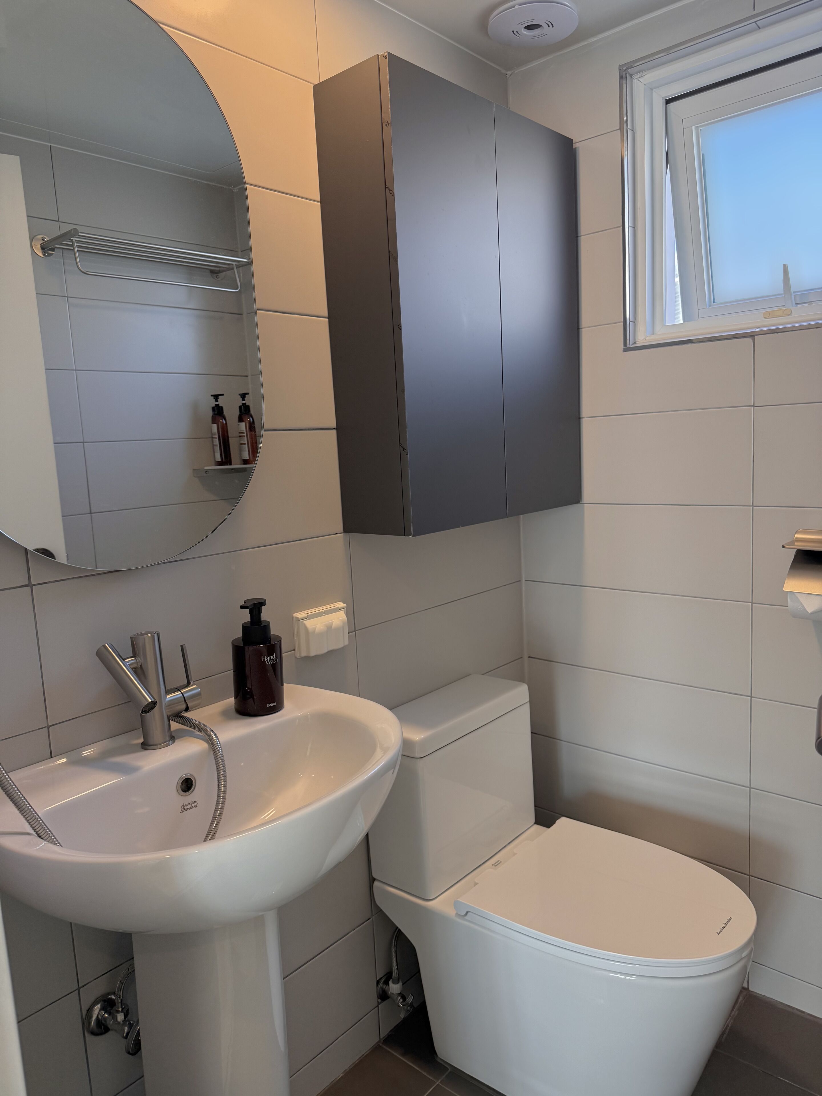 A modern bathroom with a white sink, a toilet, and a mirror.