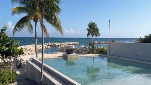 A pool with a view of the ocean, surrounded by palm trees and a rocky shoreline. - VILLAS MIA FRONT BEACH  (Xpu-Ha)