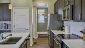 A modern kitchen with dark cabinets, stainless steel appliances, and a white countertop. - Family Friendly 5BR Mountain Views & Game Room with AC (Superior)