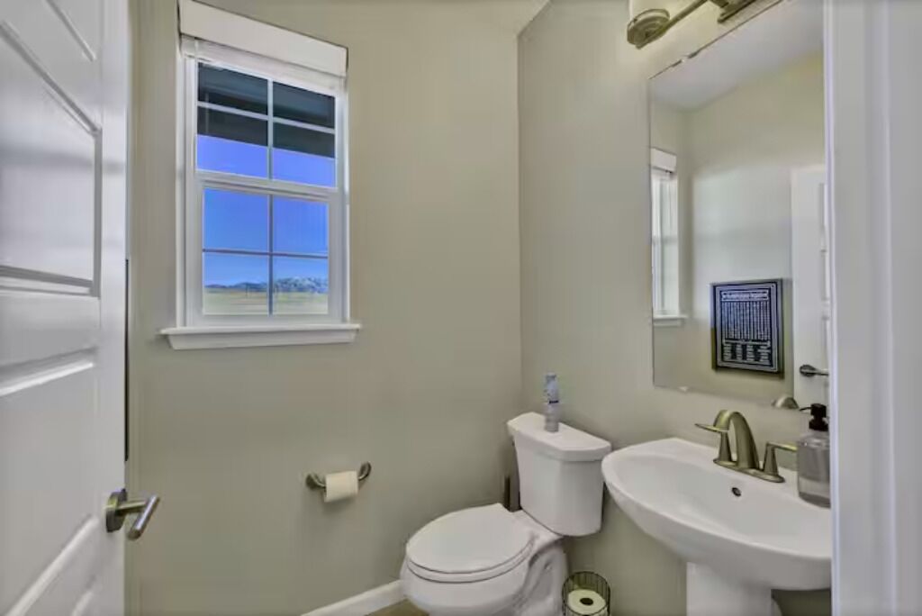 Een kleine badkamer met toilet, wastafel en raam.