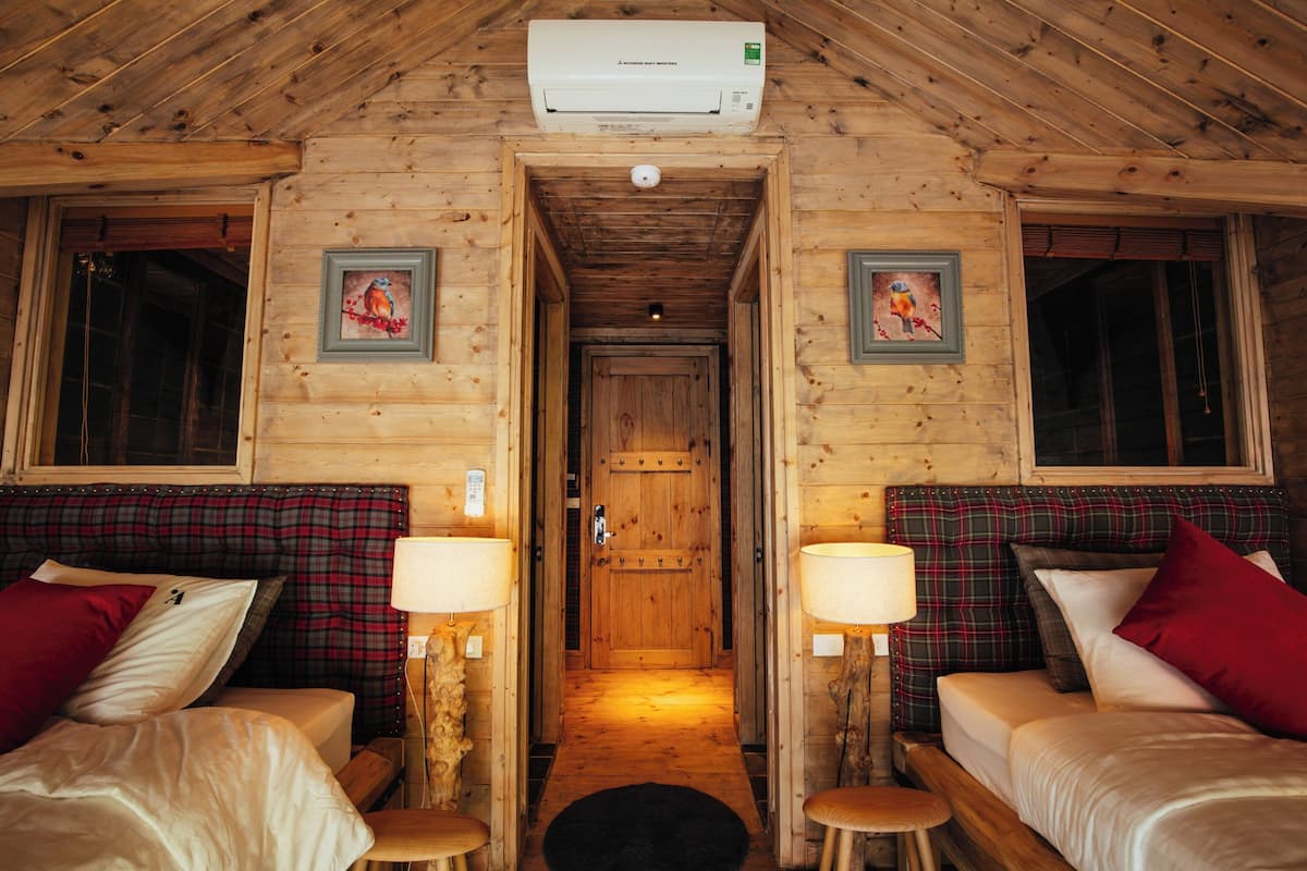 Eine Holzhütte mit zwei Betten, einem Flur und einer Tür.