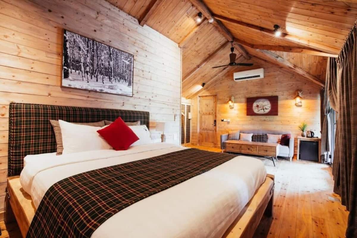 Ein schlafzimmer im Blockhausstil mit einem großen Bett, einer Holzbalkendecke und einem Kamin.