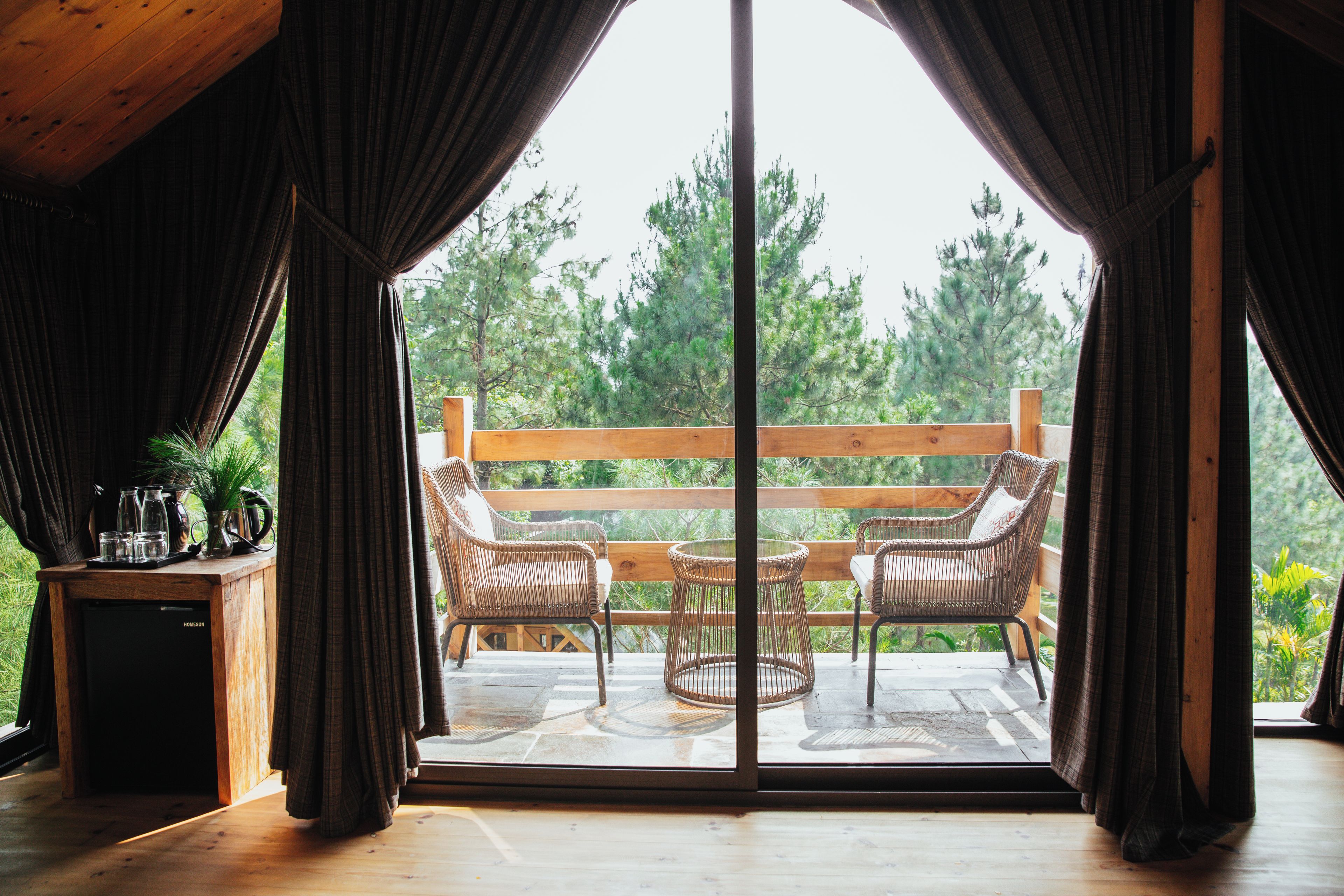 A room with a large sliding glass door leading to an outdoor deck with wicker furniture and a view of trees.