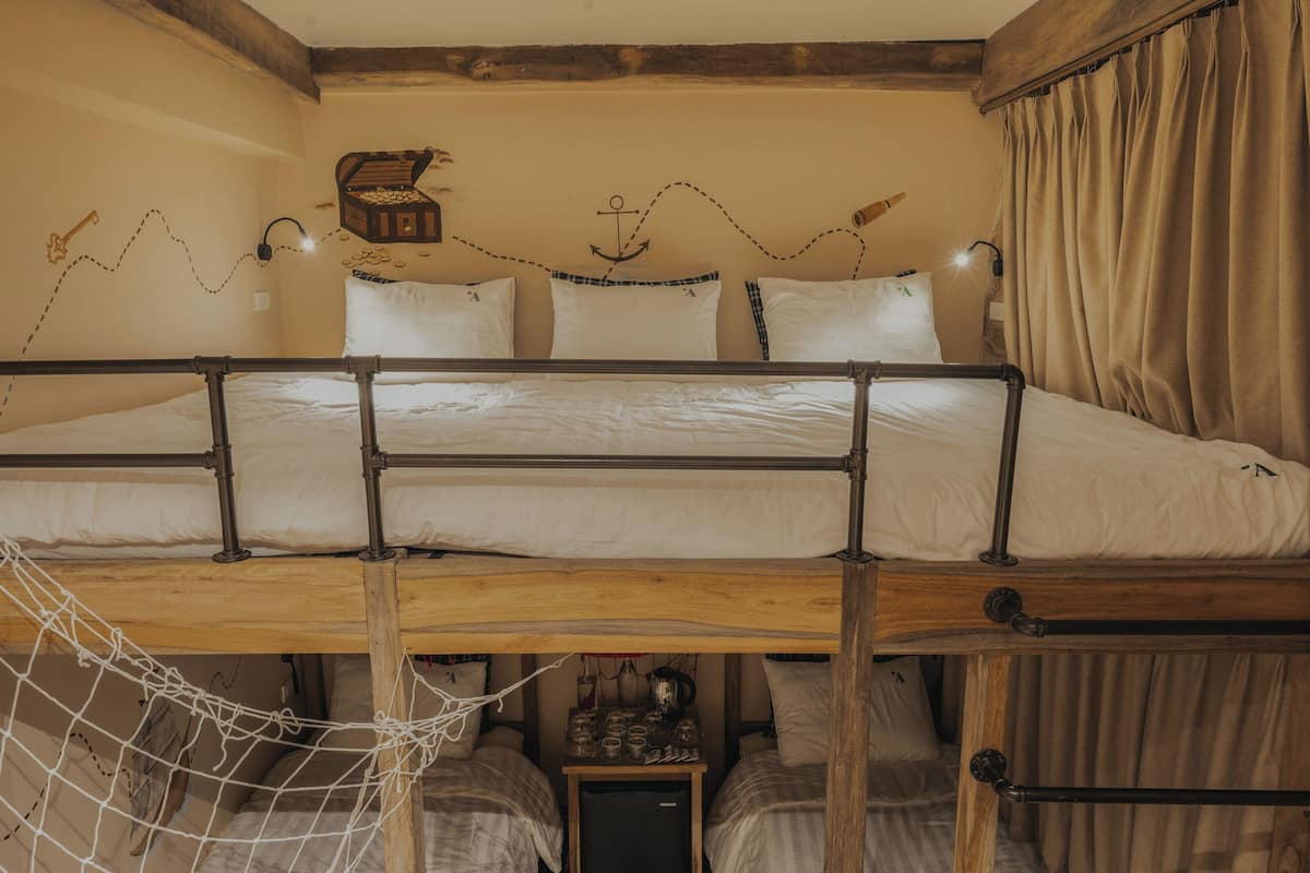 Ein Schlafraum mit Etagenbetten, Holzboden und einer kleinen Tischplatte mit Gläsern, sowie einer dekorativen Wand.