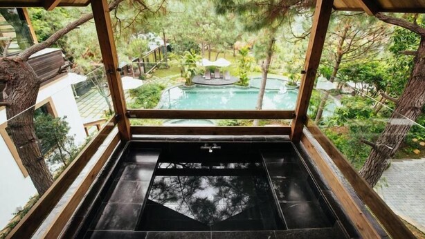 A view from a covered area with a pool and outdoor seating, surrounded by trees. - Amaya Home Lodge, SPA & Restaurant (Hanoi)