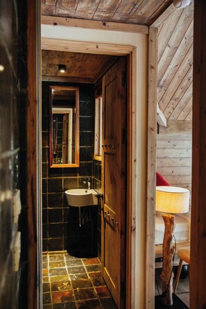 A wooden interior with a tiled floor, a sink, and a mirror. - AMAYA Forest Retreat Hanoi – a Boutique Resort & Spa (Hanoi)