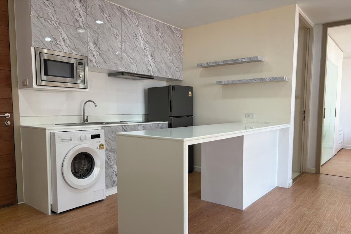 Une cuisine compacte équipée d’un lave-linge, d’un four à micro-ondes et d’un réfrigérateur.