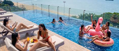 Área de piscina com espreguiçadeiras e vista para o mar.