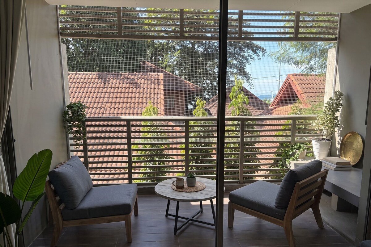 Un balcon avec deux chaises, une petite table et des plantes en pot.