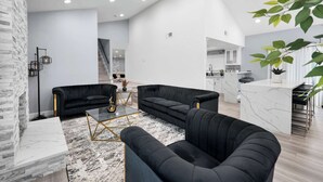 A modern living room with black sofas, a marble coffee table, and a white fireplace. - Glendora Super House! (Glendora)