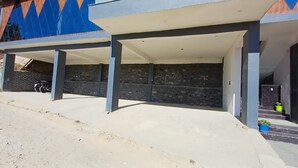 Ett takförsett utomhusområde med ett betonggolv, stenmurar och en blå och orange vägg i bakgrunden.