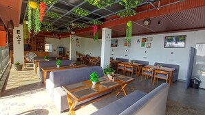 En restaurang med sittplatser inomhus, hängande växter och en meny som är tydligt synlig.