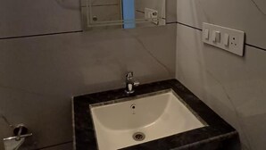 Ett badrum med ett rektangulärt handfat, en spegel och en lampa monterad ovanför spegeln.