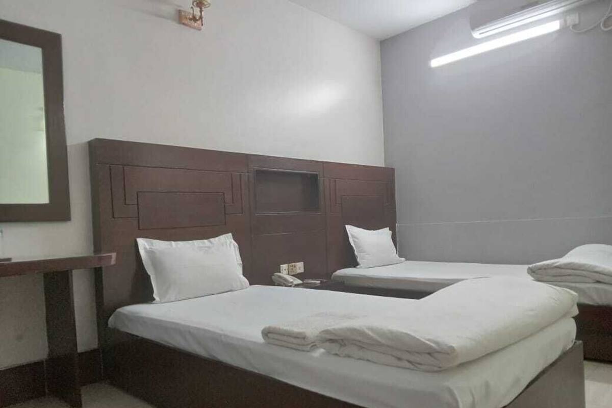 Ein Hotelzimmer mit zwei Betten, einem Holzkopfteil, einem Nachttisch und einem Spiegel.