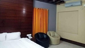 Une chambre d’hôtel avec un lit, une chaise, un rideau et un appareil de climatisation.