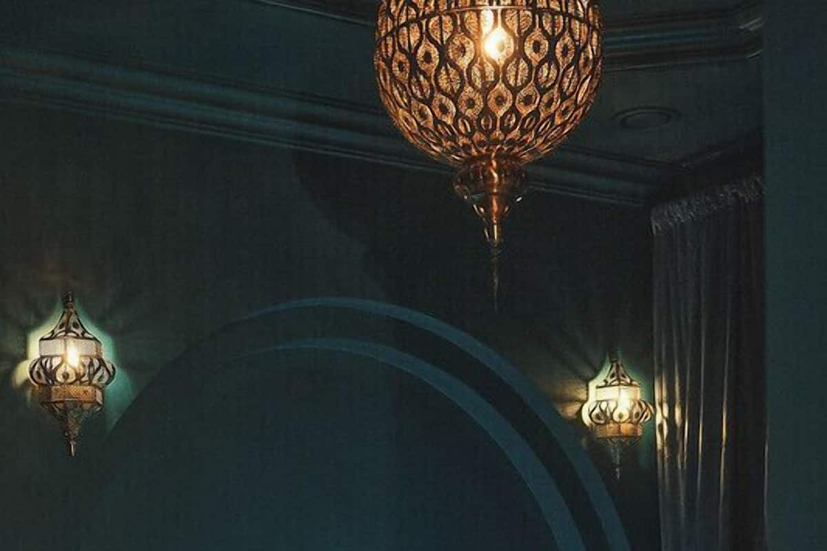 A bedroom with a bed, two wall-mounted lamps, and a large, ornate ceiling light fixture.