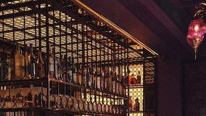 A bar area with a wine rack, bar counter, and teal chairs. - Riad Luxury Hotel Hanoi (Hanoi)