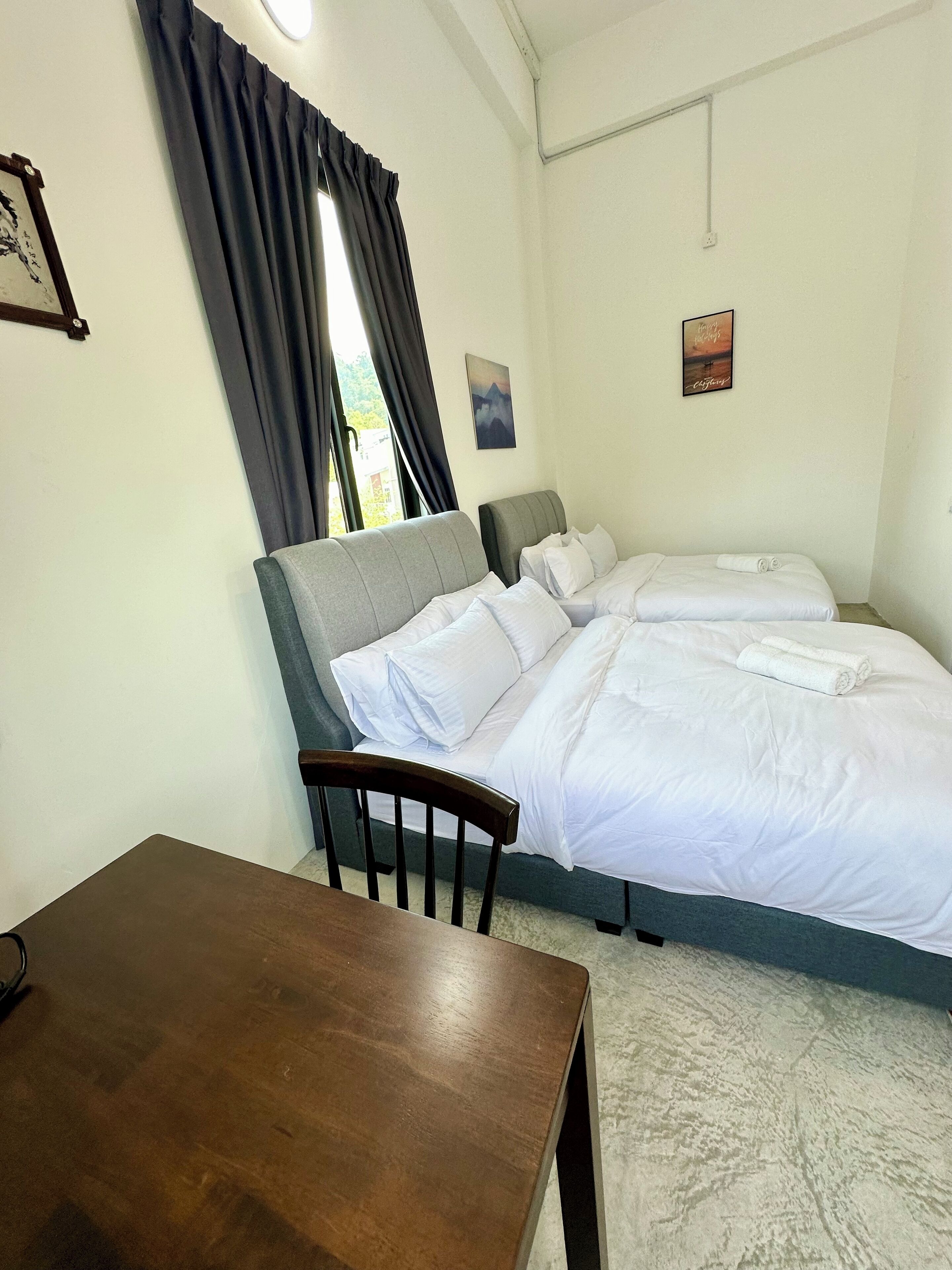 Una habitación de hotel con cama, una mesa de madera y una ventana con cortinas.