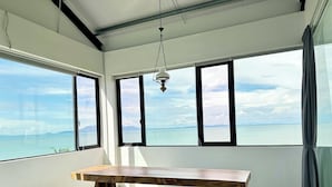 A spacious room with a large wooden table, large windows with black frames, and a hanging light fixture. - Ferringhi Inn 51 (George Town)