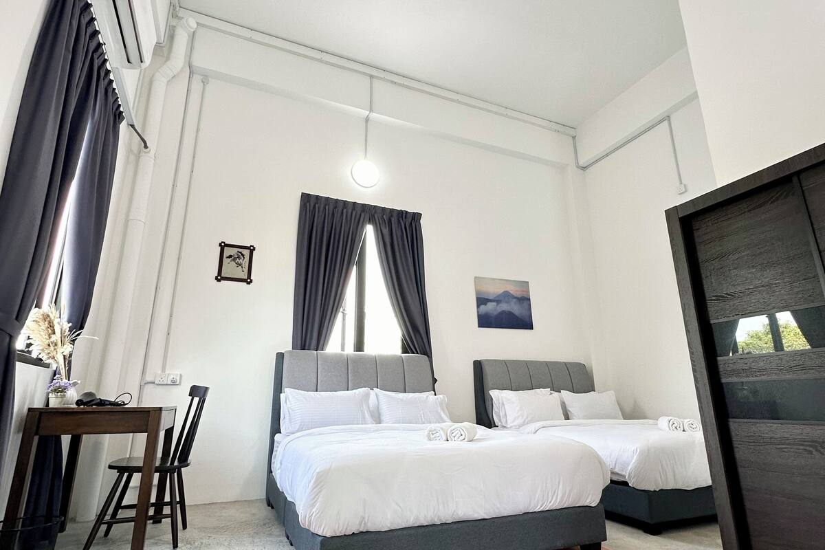 A modern hotel room with two beds, a desk, and a large window with curtains.