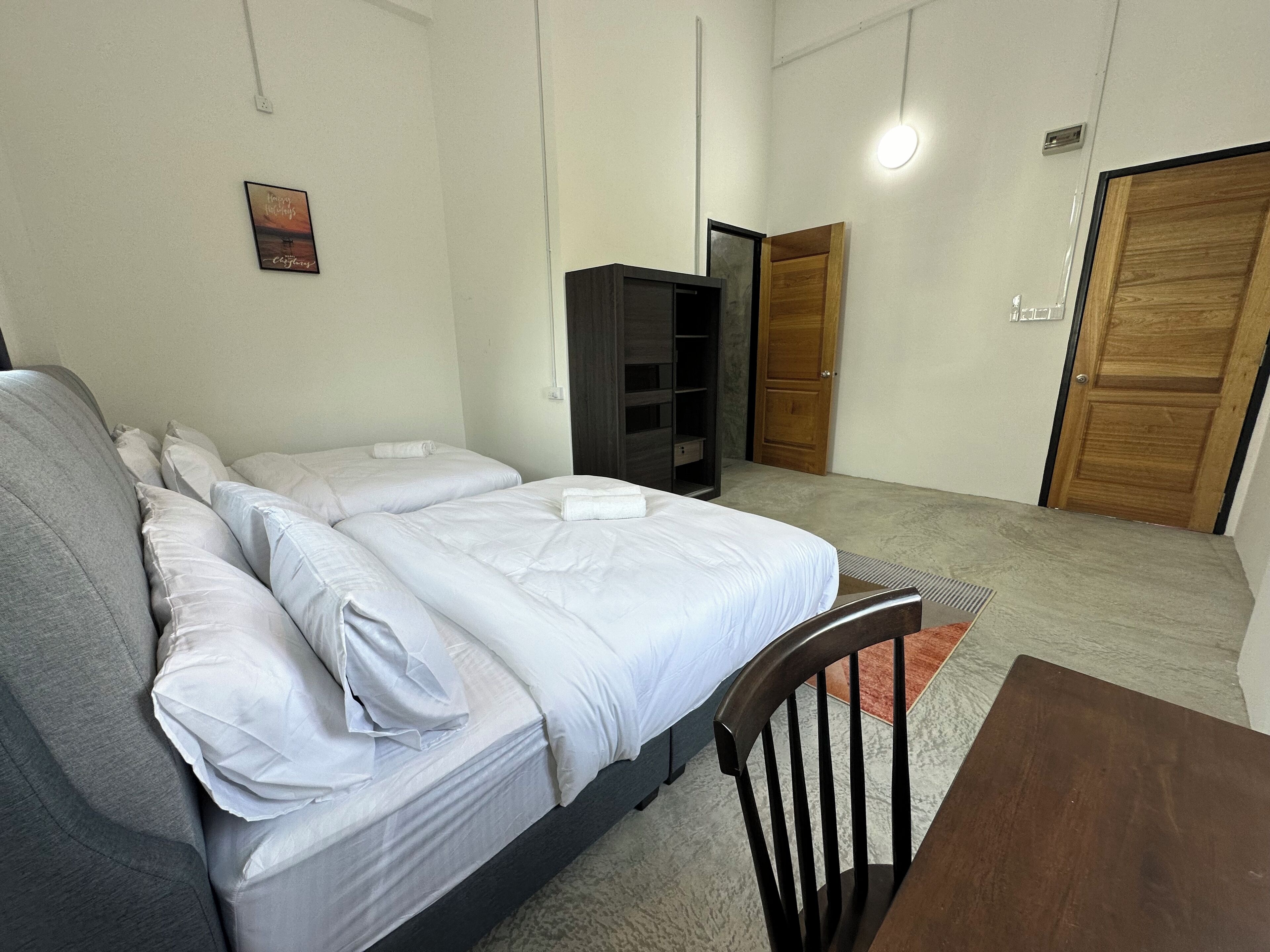 Une chambre avec deux lits, une armoire en bois, une petite table et une porte.