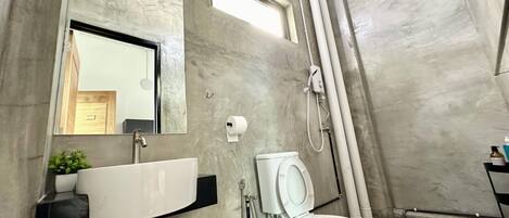 Un baño moderno con pared de mármol, un lavabo blanco, inodoro y ducha.