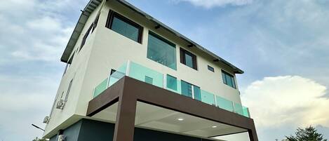 A two-story building with a flat roof and a balcony.