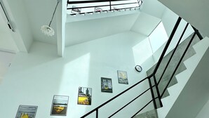 A modern interior with a staircase, a ceiling light, and framed pictures on the walls. - Ferringhi Inn 51 (George Town)