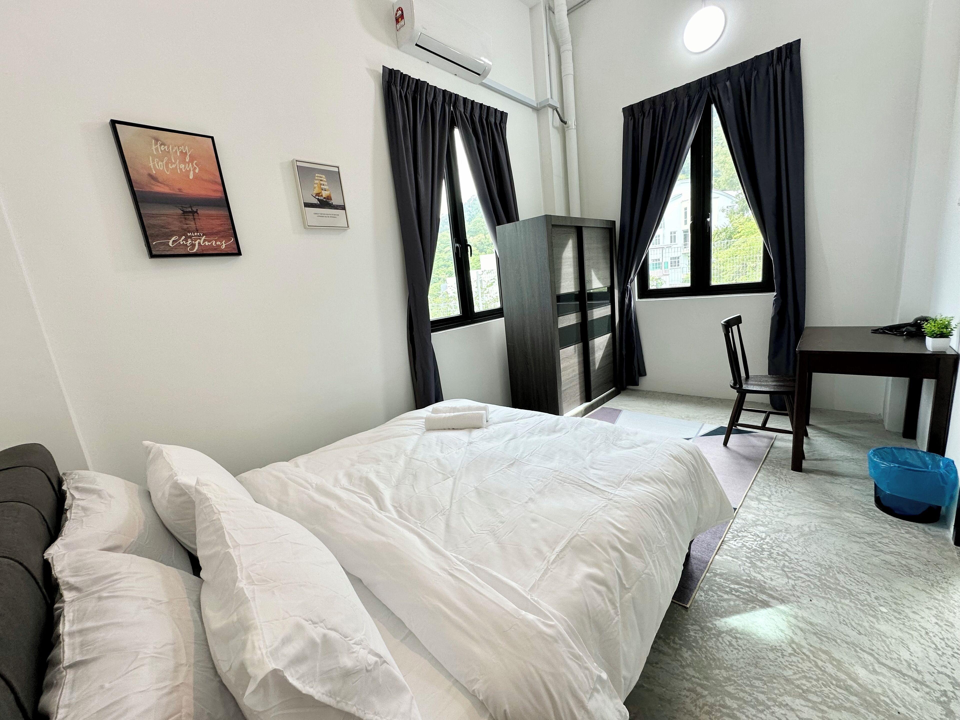 A hotel room with a bed, a desk, a chair, a small table, and a window with curtains.