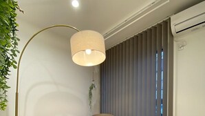 Ein stilvoller Essbereich mit einem runden Holztisch, zwei Stühlen, einer Stehlampe und einer hängenden Pflanze.